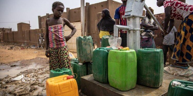 Des déplacés venus du Burkina Faso dans un camp ivoirien et en train de s’approvisionner dans en eau.